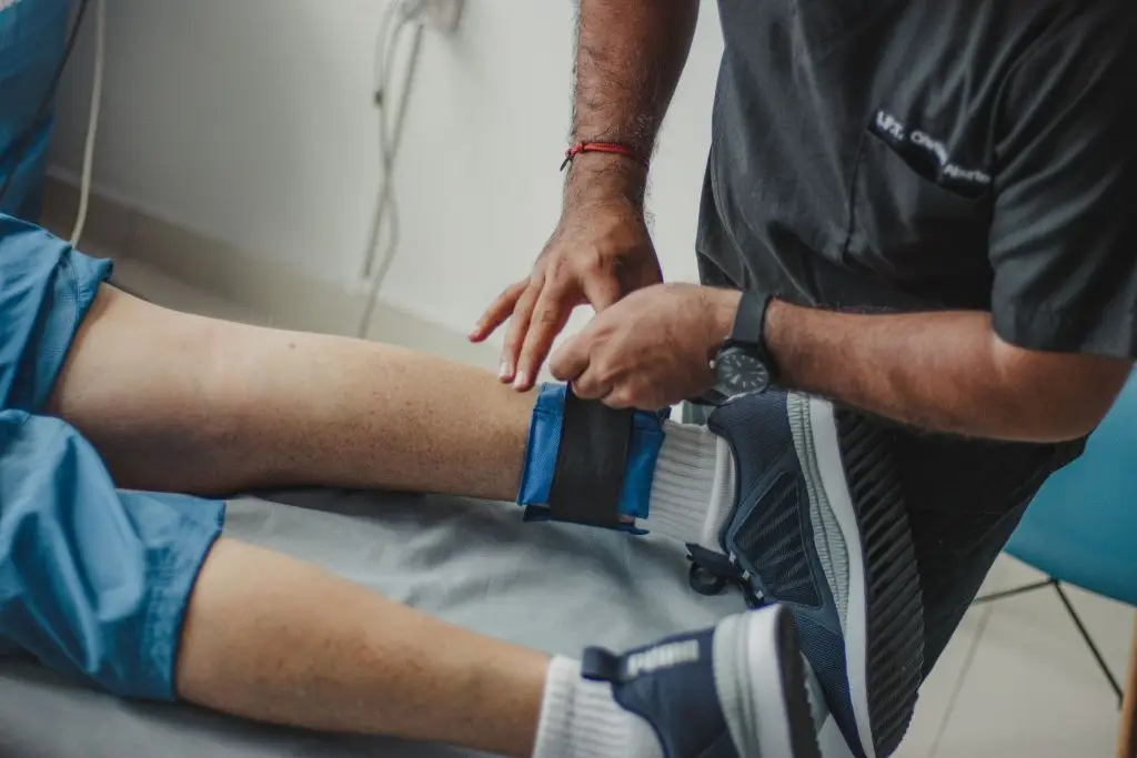 https://www.pexels.com/photo/physiotherapist-standing-over-patient-lying-down-13538710/